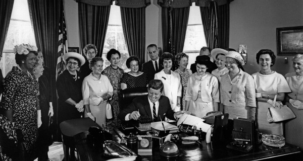 AAUW members Minnie Miles (front row, fourth from right) and Reps. Edith Green (left of president, in white suit), Martha Griffiths (second from right), and Julia Hansen (far right) with President John F. Kennedy as he signs the Equal Pay Act into law on June 10, 1963. CREDIT: Abbie Rowe, White House Photographs. Courtesy of John F. Kennedy Presidential Library and Museum, Boston